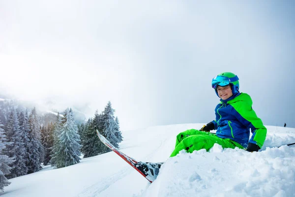 Widok Boku Chłopca Narciarstwa Alpejskiego Siedzieć Śniegu Nad Śnieżnym Lesie — Zdjęcie stockowe