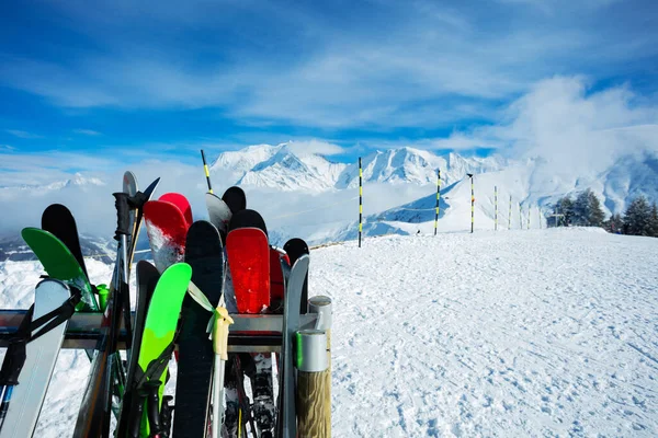 Many different alpine skis over mountain summit peaks and clouds on background on ski resort