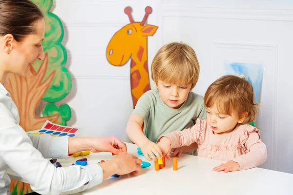 Felnőtt Két Kis Óvodás Gyerekek Építeni Torony Színes Blokkok Asztalon — Stock Fotó