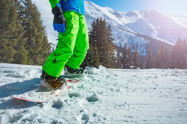 Close Van Een Snowboarder Benen Het Bord Met Besneeuwde Bergen — Stockfoto