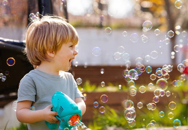 Little boy play with soap bubbles gun it the playground laugh and smile