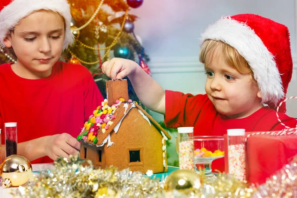 Two Boys Santa Hat Gluing Together Gingerbread House Christmas — ストック写真
