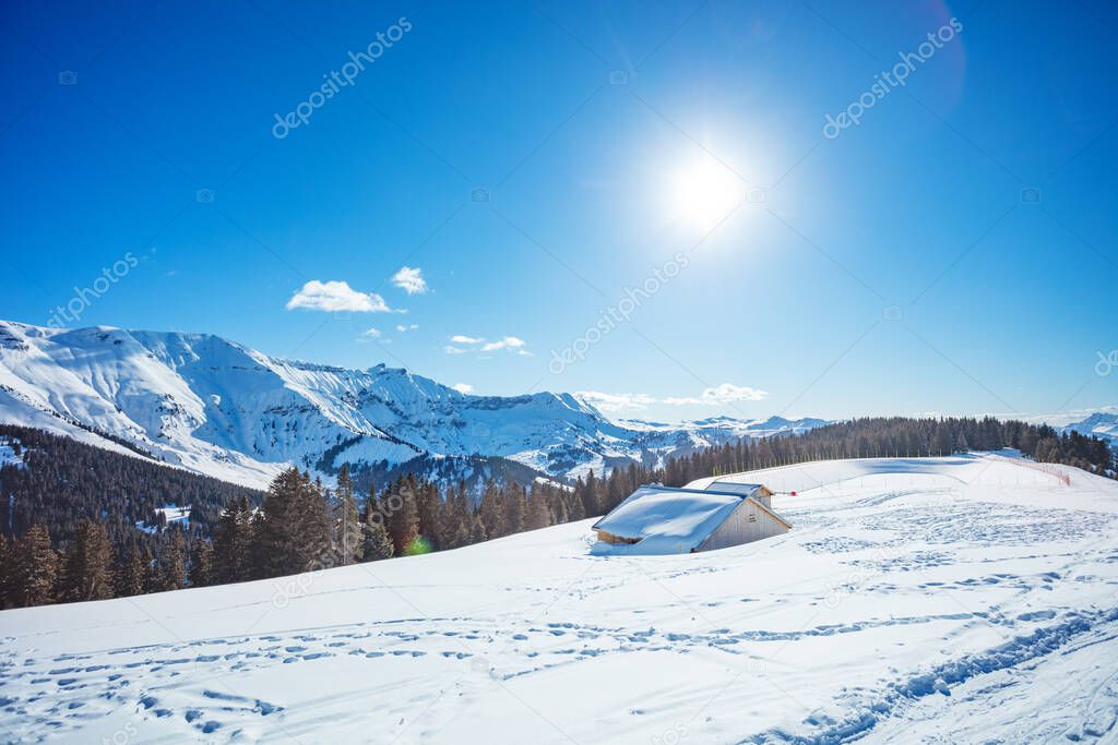 Alps mountain panorama with almost covered by snow after strong snowfall cottage house and bright sun in the sky