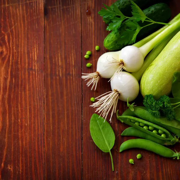 Verse groene groenten en kruiden op een donkere achtergrond — Stockfoto