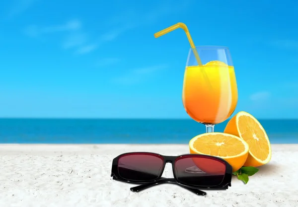 Zumo de naranja y gafas de sol en la playa — Foto de Stock