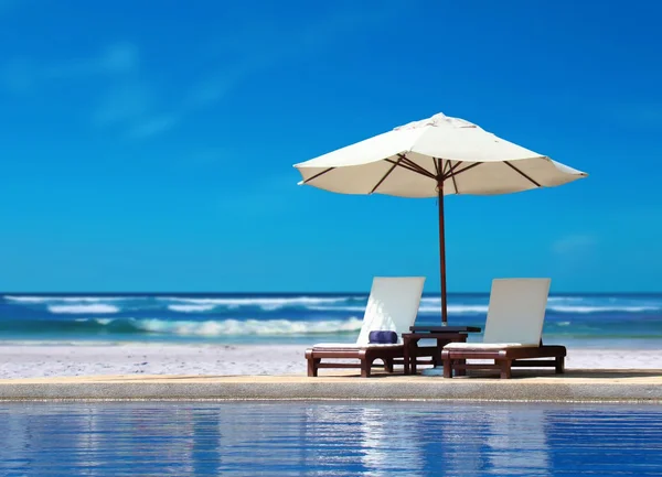 Два стула с белыми зонтиками у пляжа — стоковое фото