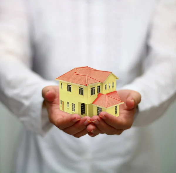 Handhaltendes Miniaturhaus Wohnungsbaukreditkonzept lizenzfreie Stockfotos