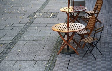 Güneşli bir caddede bir kafede masa ve sandalyeler                               