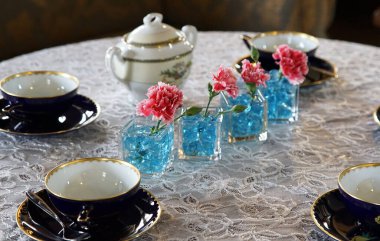 Masada fincanlar, saksılar ve çiçek süslemeleriyle çay zamanı                               