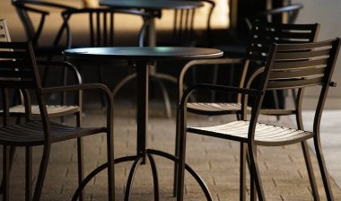 Kasaba meydanındaki bir kafede sandalye ve masaların gece görüşü                               