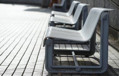 Güneşli bir günde meydanda banklar ve kaldırım taşları                               