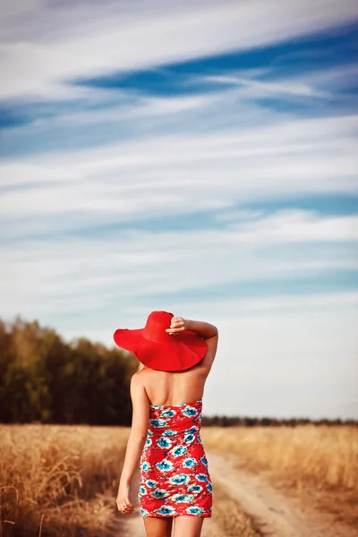 Κορίτσι στο κόκκινο φόρεμα με κόκκινο καπέλο στο πεδίο — Φωτογραφία Αρχείου