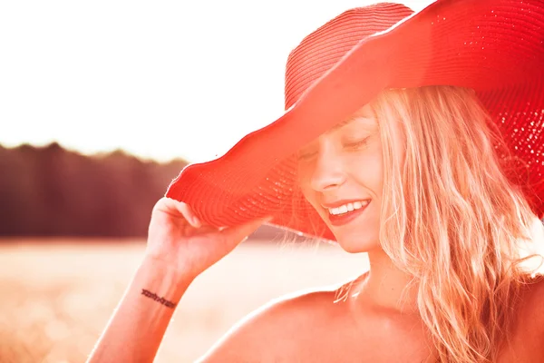 Närbild av en leende ung kvinna poserar med en hatt — Stockfoto