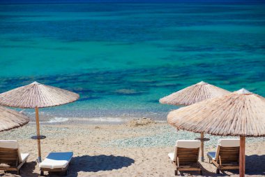 Sandalyeler ve şemsiyelerle kumsal manzarası