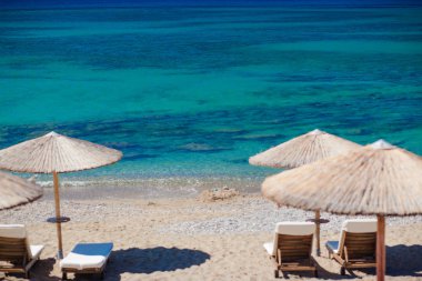 Sandalyeler ve şemsiyelerle kumsal manzarası