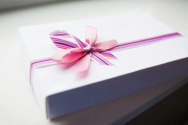 Weiße Geschenkschachtel mit farbigem Band — Stockfoto