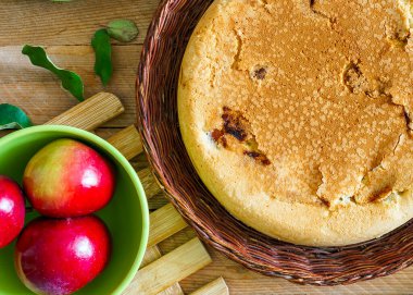 Ahşap bir masada hasır bir tabakta ev yapımı elmalı turta.