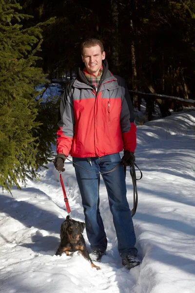 The man in a red jacket, standing on a footpath, holds on a lead — Stock Photo, Image