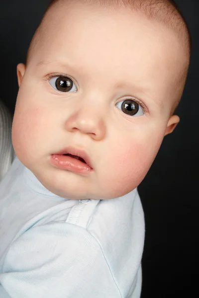 El bebé en la camiseta de un bebé azul se ve en una lente —  Fotos de Stock