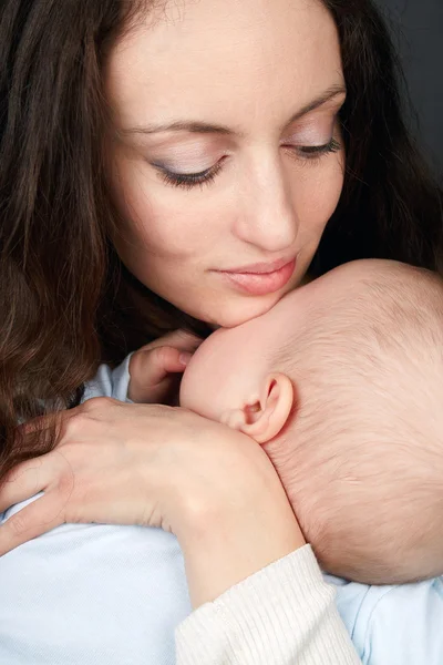 The young woman looks at the son nestling on it in a blue baby's — Stock Photo, Image