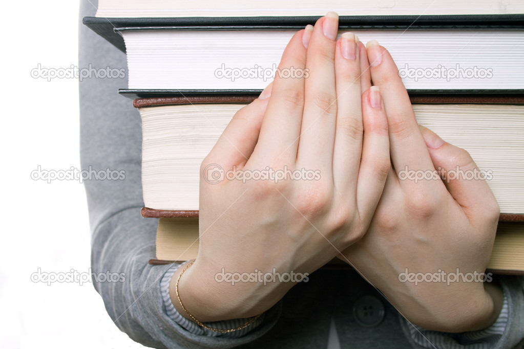 The girl holds a heavy pile of books on hands
