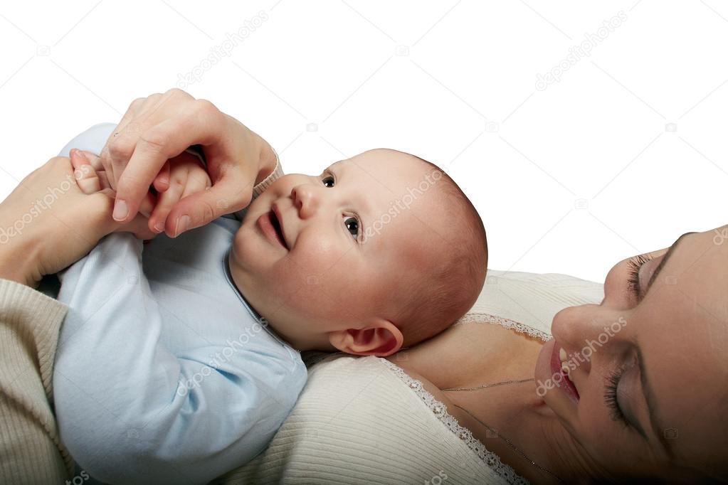 The baby in a blue baby's undershirt lies on a breast at mother