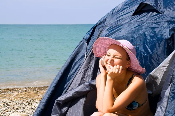 Girl calls by phone, sitting in tent on beach — Stock Photo, Image