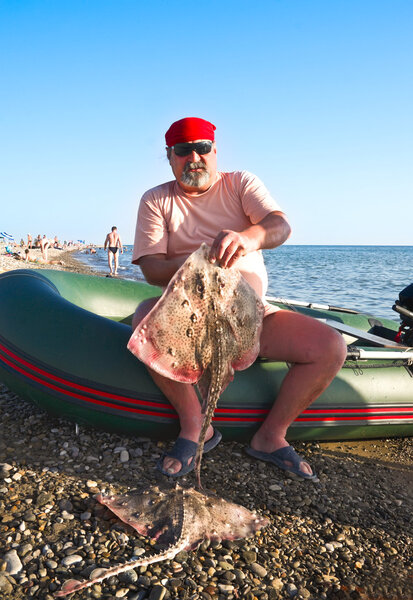 Рыбак с рыбой на пляже
