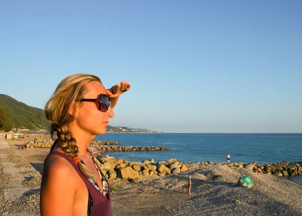 Woman under hand looks at sea in evening sunlight — Stock Photo, Image