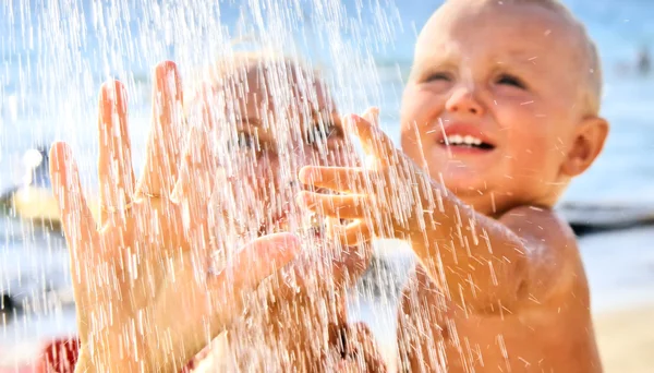 Moeder en baby onder stromend water op het strand — Stockfoto