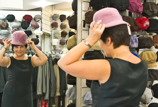 Mujer probándose el sombrero en la tienda —  Fotos de Stock