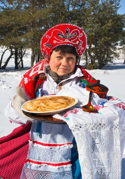 Stuk. Russische vrouw in sundress houden een plaat met pannenkoeken — Stockfoto