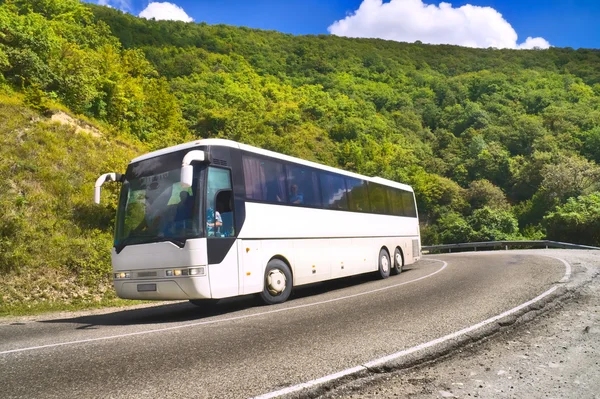 Tourist bus traveling on road among mountains — Stock Photo, Image