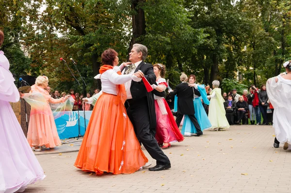 На городской площади танцуют пожилые пары в бальных костюмах — стоковое фото