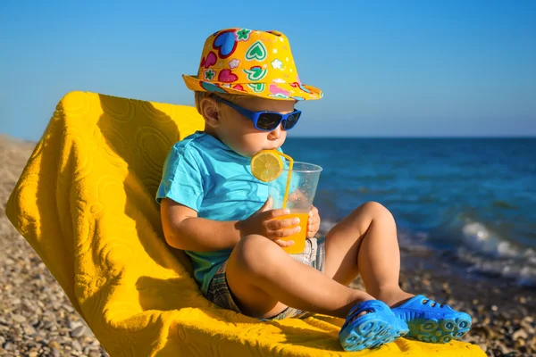 Jongen baby in zonnebril en hoed op strand dranken SAP — Stockfoto