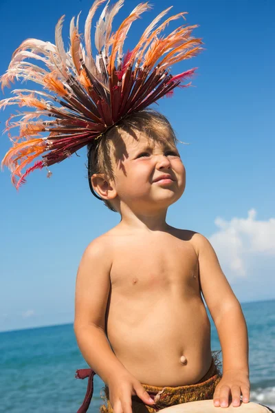 Baby boy in African feathers on head on sea coast — Stock Photo, Image