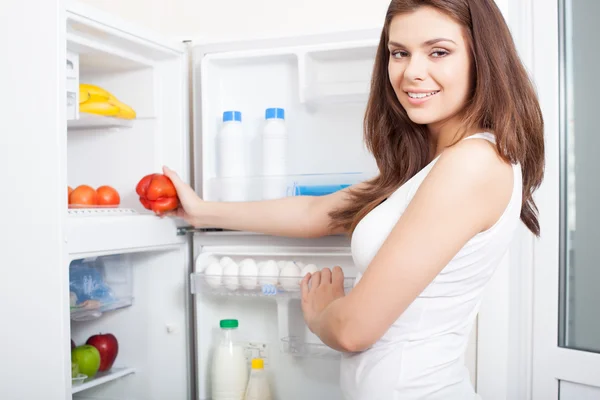 Mulher tomando pimenta da geladeira — Fotografia de Stock