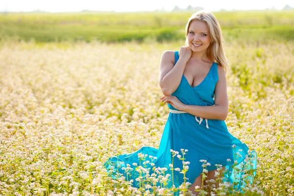 Leende kvinna bär blå klänning på ett fält — Stockfoto