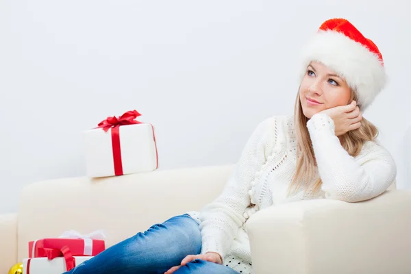 Frau sitzt auf Sofa und hält Weihnachtsgeschenk in der Hand — Stockfoto