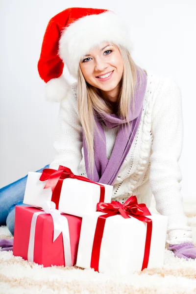 Frau mit Weihnachtsmütze sitzt auf dem Boden Stockbild