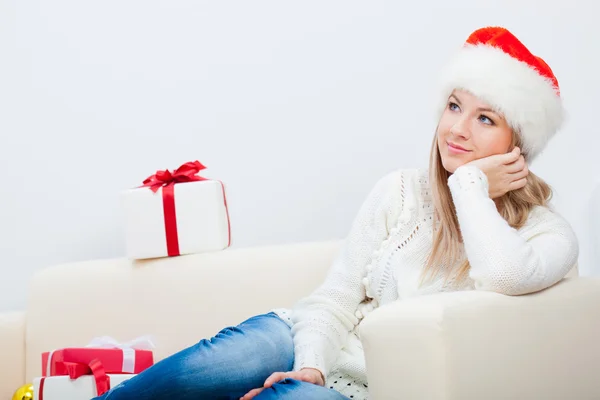 Женщина сидит на диване и держит рождественский подарок Стоковое Фото