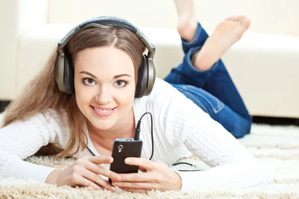 Mujer acostada en la alfombra y escuchando música —  Fotos de Stock