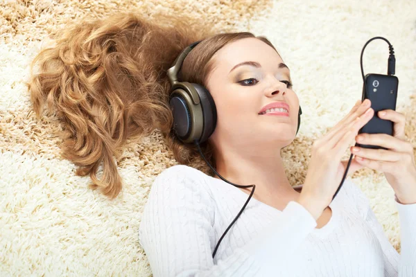 Femme couchée sur le tapis et écoutant de la musique — Photo