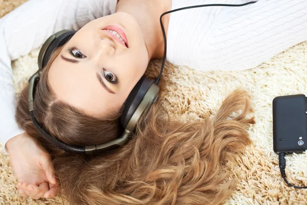 Femme couchée sur le tapis et écoutant de la musique Image En Vente