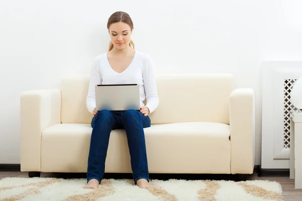 Femme heureuse assise sur un canapé avec ordinateur portable — Photo