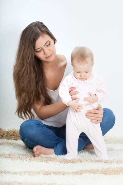 Jovem mãe brincando com o bebê no tapete — Fotografia de Stock