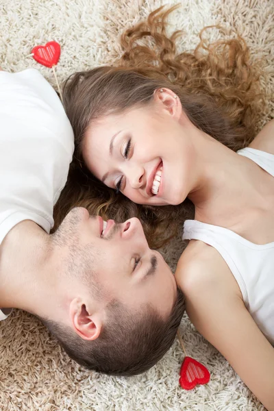 Pareja joven acostada en la alfombra — Foto de Stock