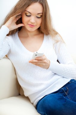 vrouw zittend op een bank en kijken naar haar telefoon