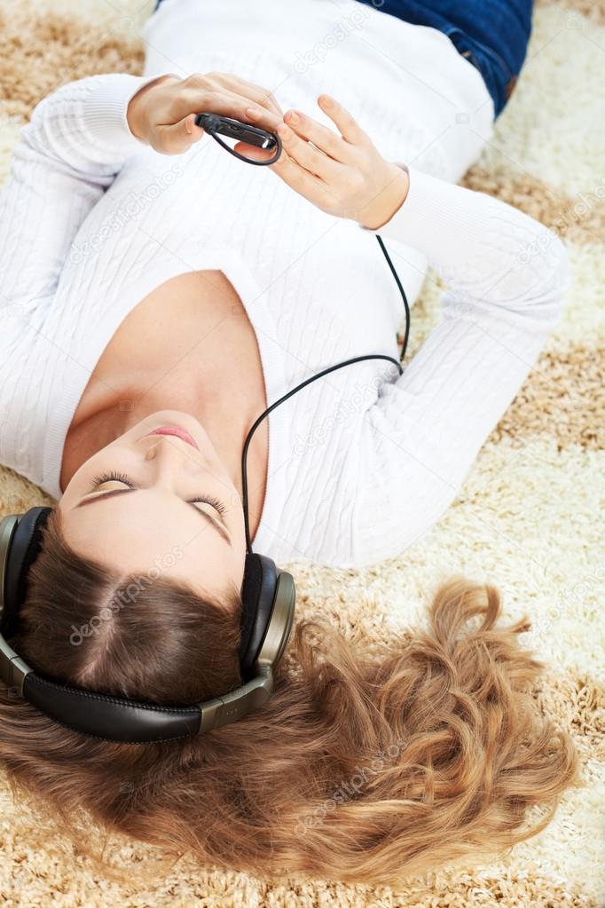 Woman lying on carpet and listening to music