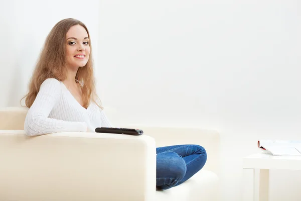 Mujer sentada en sofá con control remoto — Foto de Stock